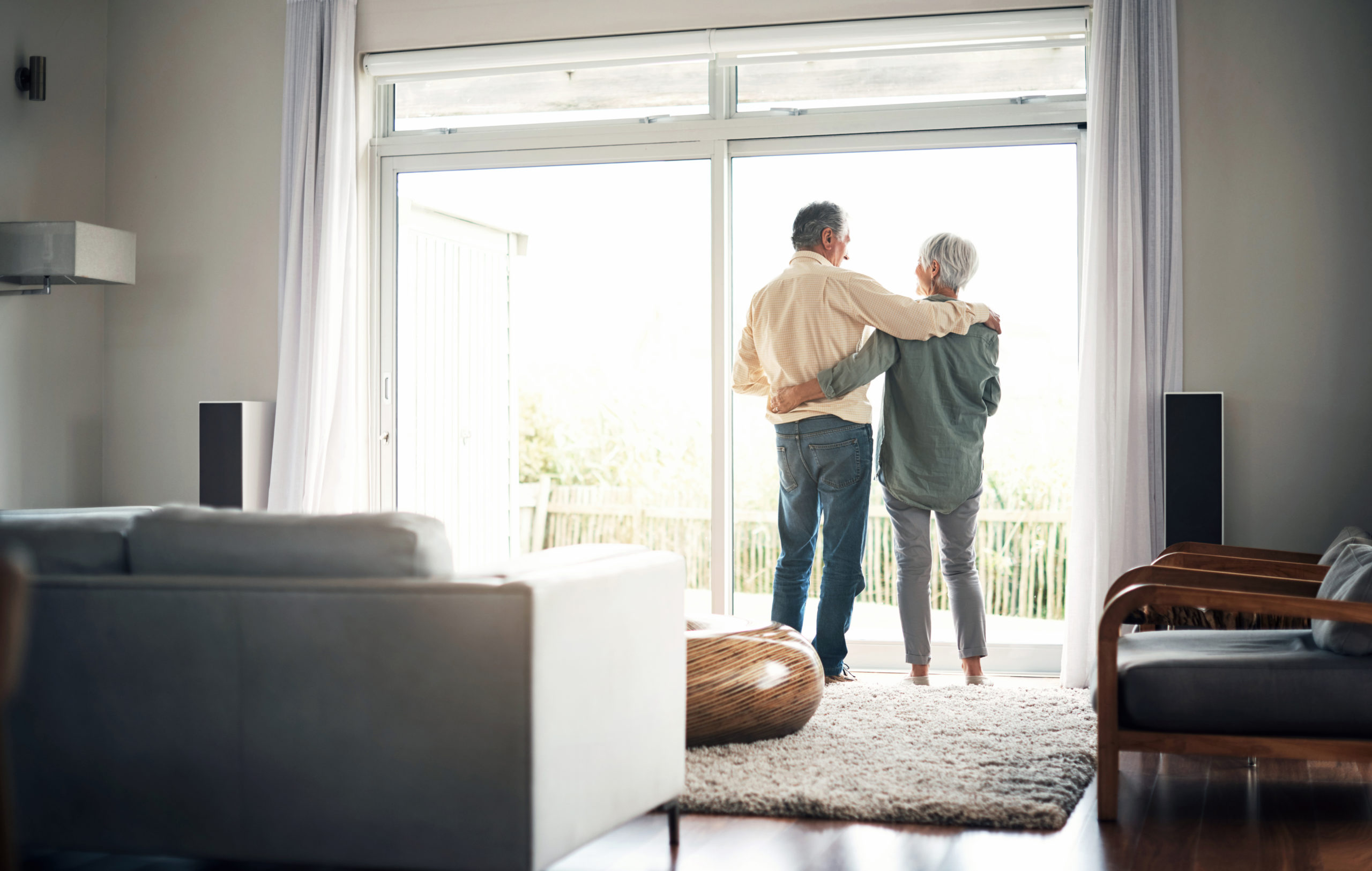 Rearview shot of an elderly couple looking out of their house together during a relaxing day at home happily ever after